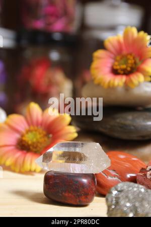 Quarzkristall auf Bloodstone mit Blumen im Hintergrund mit flachem Freiheitsgrad Stockfoto
