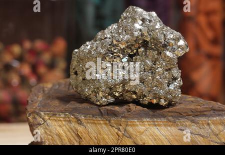 Pyrit-Probe auf rohem Tigers Eye Rock mit getrockneten Kräutern im Hintergrund Stockfoto