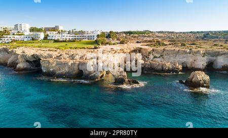 Luftaufnahme der Küste und Wahrzeichen Love Bridge, internationaler Skulpturen Park und Meereshöhlen, Cavo Greco, Ayia Napa, Famagusta, Zypern von oben. Stockfoto