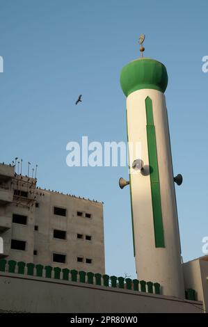 Minarett einer Moschee und schwarze Drachen auf dem Dach eines Gebäudes. Stockfoto