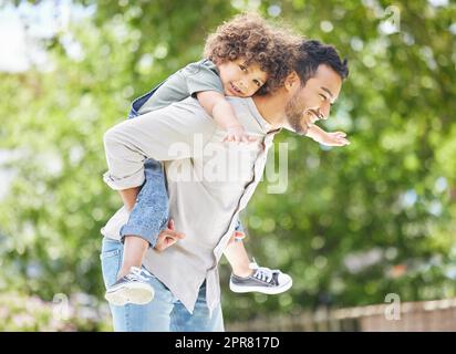 Auch ihre Bindung als beste Freunde zu wachsen. Aufnahme eines Vaters, der seinem Sohn eine Huckepack-Fahrt im Freien gab. Stockfoto