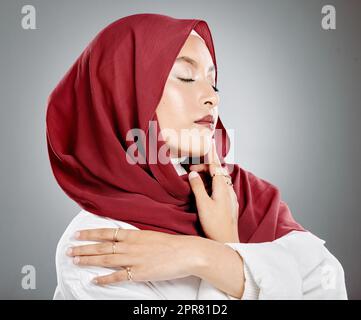 Wunderschöne muslimische Frau, die im Studio posiert und Hijab trägt. Porträtfoto eines erstaunlichen, selbstbewussten arabischen Modells vor grauem Hintergrund. Modische Frau mit Kopftuch. Eine elegante Frau in einer Kopfverpackung Stockfoto