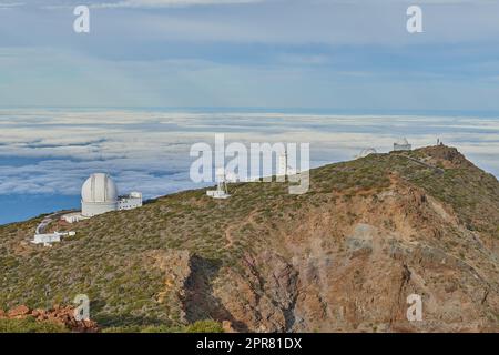 Roque de los Muchachos Observatorium in La Palma. Ein astronomisches Observatorium auf einem Berggipfel mit blauem Himmel. Das Teleskop ist von Grün umgeben und befindet sich auf einer Insel am Rand der Klippe. Stockfoto