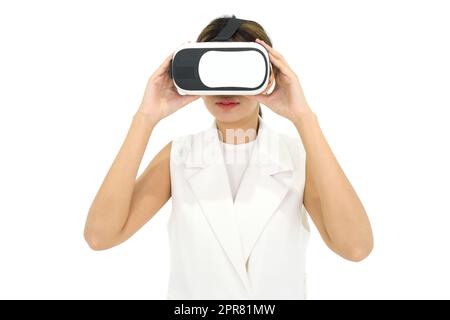 Asiatische Frau in weißem Kleid mit Virtual-Reality-Brille, spielen ein interaktives Spiel. Konzept Der Zukunftstechnologie. Stockfoto