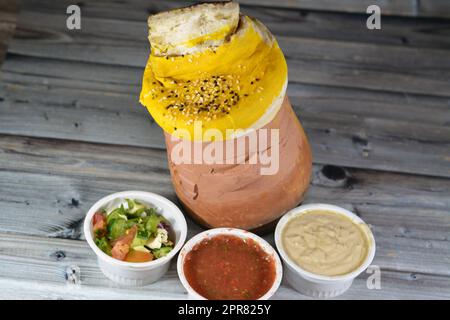 Darin befindet sich ein mit Teig, Sesam und Lammschaft bedeckter Töpferbecher mit Basmati-Reis, gemischtem Gemüse und gefüllten Traubenblättern Mahshi Ma Stockfoto