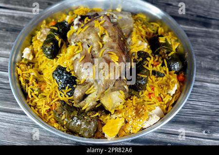 Ein gut gekochter Lammschaft mit gelbem Basmati-Reis und gemischtem Gemüse und gefüllten Traubenblättern Mahshi Mahshy mit weißem Reis, der im OV geröstet wird Stockfoto