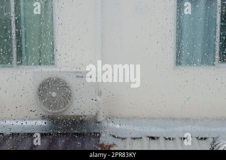 Regentropfen auf dem Fenster des Haushintergrunds Stockfoto