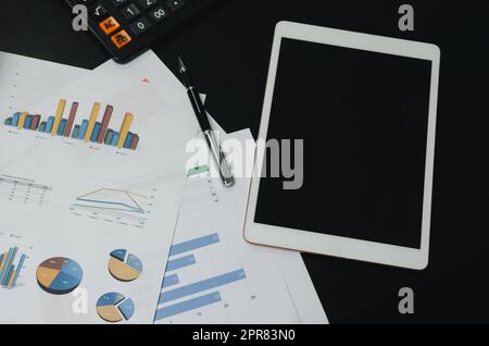 Draufsicht Dokument Diagramm Analyse Diagramm Plan Finanz- und Diagramm Bericht Informationen Wirtschafts-und Steuer mit Stift und Tablet auf schwarzem Schreibtisch. Stockfoto