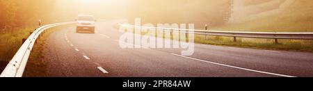 Schwarze Asphaltstraße mit Trennlinie und Sicherheitszaun im Morgennebel. Stockfoto