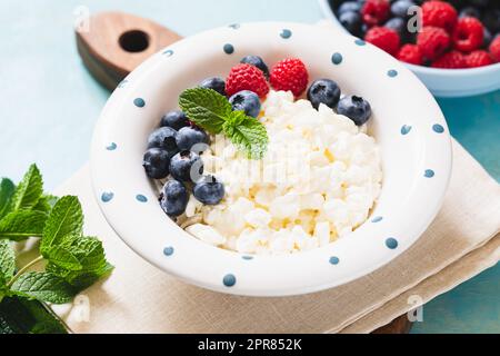 Hausgemachter Hüttenkäse mit Beeren und Minze. Quark in einer Schüssel. Milchprodukte. Stockfoto