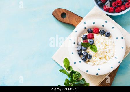 Hausgemachter Hüttenkäse mit Beeren und Minze. Quark in einer Schüssel. Milchprodukte. Stockfoto