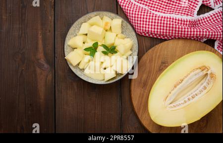 In Scheiben geschnittene Melonenstücke auf einem runden grauen Teller auf dem Tisch Stockfoto