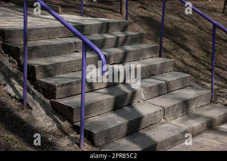 Alte Betontreppen mit purpurem Metallgeländer Stockfoto