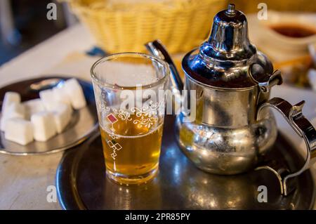 Traditioneller marokkanischer Pfefferminztee auf dem Esstisch mit Zucker zur Seite. Stockfoto