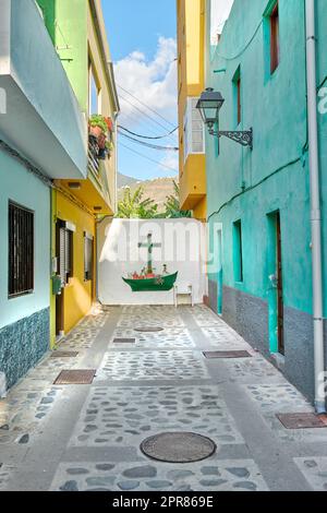 Farbenfrohe alte Gebäude mit einer Mauer mit einem Kreuz oder Kruzifix in der Stadt Santa Cruz de La Palma. Helle und lebendige Häuser oder Häuser, die morgens in traditioneller Architektur in einem Dorf erbaut wurden Stockfoto