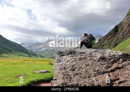 Wanderer, die sich ausruhen und die Aussicht auf einen Felsen im Berg genießen Stockfoto