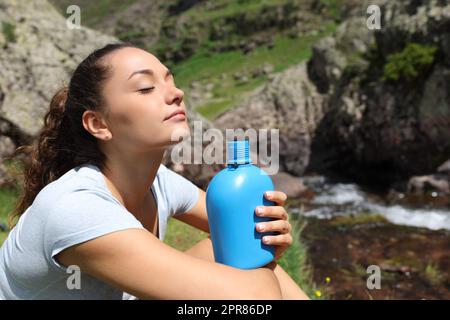 Eine Frau, die eine Kantine hält und im Berg atmet Stockfoto