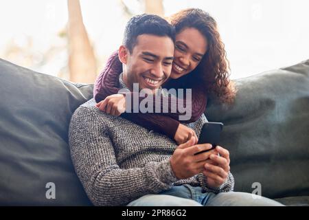 Manchmal braucht man schnell etwas, das Internet kann helfen. Aufnahme eines jungen Paares, das zusammen etwas auf einem Handy ansieht. Stockfoto