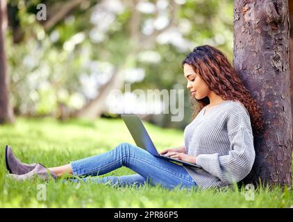 Pausen sind einfach mehr Zeit zum Lernen. In voller Länge eine attraktive junge Studentin, die ihren Laptop benutzt, um draußen auf dem Campus zu studieren. Stockfoto