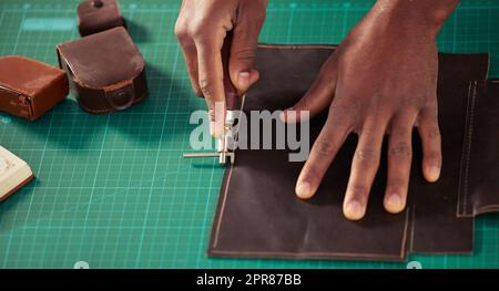Arbeiten mit seinen Händen. High-Angle-Aufnahme eines unkenntlichen männlichen Designers, der in seinem Designstudio mit Leder arbeitet. Stockfoto