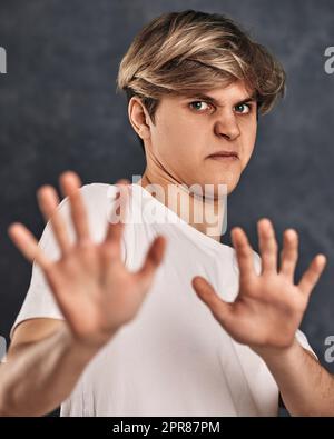 Junger Mann, der Negativität auf grauem Hintergrund ausdrückt. Stockfoto