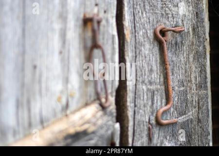 Isoliertes altes rostiges Türschloss an einer Holztür. Nahaufnahme. Problematische verwitterte Platten. Hintergrund der alten Wandtextur. Detail einer alten Holztür mit rostigem Türschloss. Stockfoto