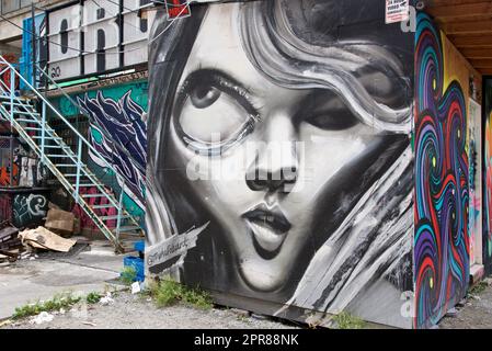 Toronto, Ontario/Kanada - 24. September 2022: Eine Frau fotografiert farbenfrohe Graffiti an der Wand in einer Gasse in Toronto, Ontario, Kanada Stockfoto