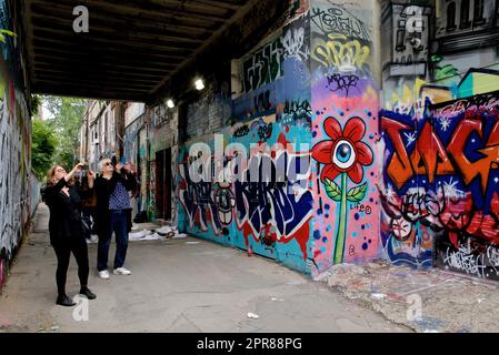 Toronto, Ontario/Kanada - 24. September 2022: Eine Frau fotografiert farbenfrohe Graffiti an der Wand in einer Gasse in Toronto, Ontario, Kanada Stockfoto