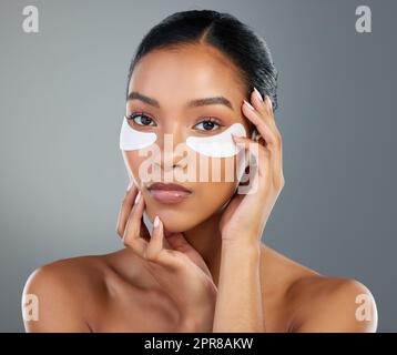 Habe es beim ersten Mal ausprobiert und nie aufgehört, es zu verwenden. Studioaufnahme einer schönen jungen Frau, die unter den Augen Flecken trägt. Stockfoto