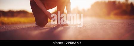 Sportliche Frau, die Schnürsenkel am Schuh bindet, bevor sie mit dem Laufen beginnt. Stockfoto