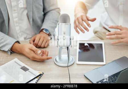 Machen wir eine kurze Pause, bevor wir wieder in den Konvo springen. Nahaufnahme von zwei Geschäftsleuten, die während einer Sendung in einem Büro ein Mikrofon benutzten. Stockfoto