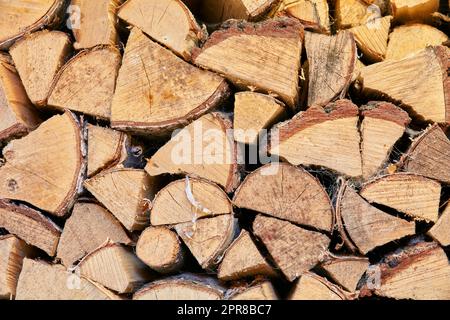 Holz gehackt und in einen Lagerstapel gestapelt. Brennholz als Energiequelle sammeln. Verschiedene Größen und Formen von Stämmen nach dem Fällen, Werkstoffe für Werkzeuge und Unterstände von oben Stockfoto