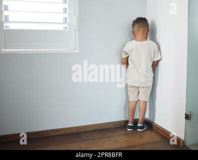 Er hasst es nicht, seinen Weg zu finden. Aufnahme eines unerkennbaren kleinen Jungen, der zur Wand zeigt und als Strafe in einem Zimmer zu Hause eingesetzt wird. Stockfoto