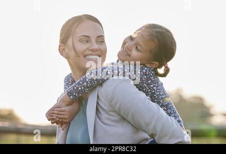 Niemand sieht dich so an, wie es deine Tochter tut. Ein entzückendes kleines Mädchen, das mit ihrer Mutter auf ihrem Bauernhof eine Huckepack-Fahrt genießt. Stockfoto