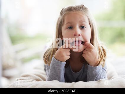 Ich Frage mich, ob mein Gesicht so bleiben wird. Ein junges Mädchen, das zu Hause lustige Gesichter macht. Stockfoto