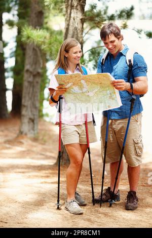 Ein Paar, das eine Pause vom Wandern und dem Betraten der Karte nimmt. Ein glückliches Paar, das eine Pause vom Wandern macht und auf einer Karte nach dem Weg sucht. Stockfoto