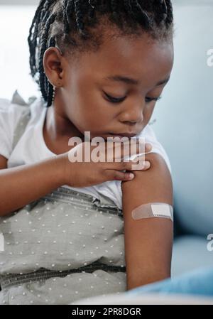 Impfen, um Ihr Kind vor vielen gefährlichen Krankheiten zu schützen. Aufnahme eines entzückenden kleinen Mädchens mit einem Gips auf ihrem Arm nach einer Injektion. Stockfoto