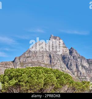 Landschaftsblick und blauer Himmel mit Kopie des Tafelbergs in Westkap, Südafrika. Steiles, landschaftlich berühmtes Wander- und Trekkinggebiet mit Bäumen im Umkreis. Fahrt mit der Seilbahn zum Gipfel Stockfoto