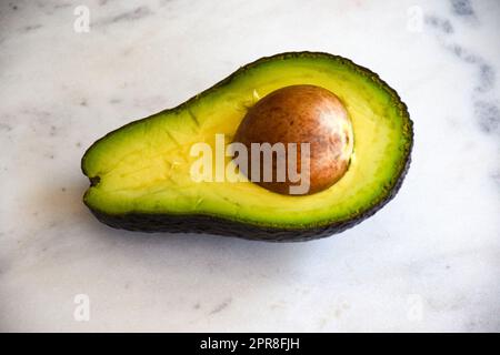 Avocado halb auf weißem Hintergrund, halb Avocado Stockfoto