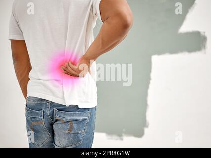 Das ist wirklich anstrengend. Aufnahme eines Mannes, der Rückenschmerzen hatte, während er zu Hause mit dem Malen beschäftigt war. Stockfoto