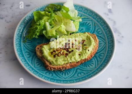 Avocado auf Toast, Guacamole auf Brot, leckeres Frühstück, Keto-Diät-Idee, köstliche gesunde und nahrhafte Mahlzeit, Brunch-Idee, weißer Hintergrund, Blau Stockfoto