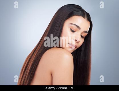 Schöne junge Frau mit glänzendem braun und geraden langen Haaren. Das junge Mädchen blickt auf ihre Schulter und zeigt gesund aussehende Haare Stockfoto