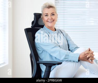 Lebe deine Leidenschaft. Porträt einer selbstbewussten, reifen Geschäftsfrau, die in einem Büro auf einem Stuhl sitzt. Stockfoto