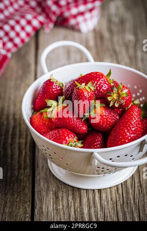 Erdbeeren in weißem Sieb auf rustikalem Holzhintergrund. Frische und leckere saisonale Reife und Früchte. Stockfoto