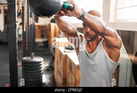 Schwingt hart und hoch. Ein junger Mann, der während seines Trainings eine Kettlebell schwingt. Stockfoto