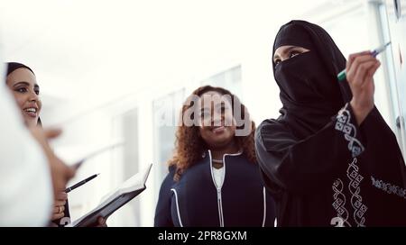 Shes hat einen Plan für die Ausführung erhalten. Aufnahme einer Gruppe verschiedener Geschäftskollegen, die in ihrem Büro an einem Whiteboard arbeiten. Stockfoto