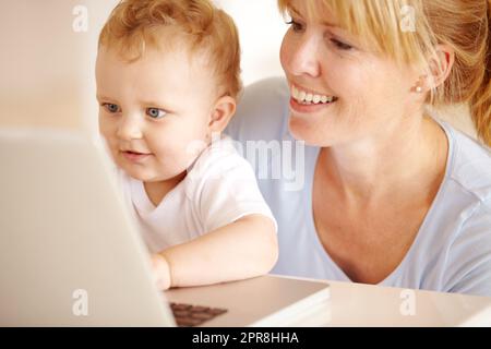 IT-Genie im Bilden. Schöne Mutter hilft ihrem kleinen Jungen Typ auf ihrem Laptop-Computer. Stockfoto