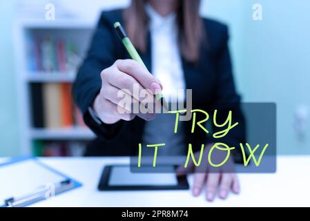 Handgeschriebenes Schild Try IT Now. Word for Free – Testversion von etwas Neuem Experimentieren Sie verschiedene Dinge Geschäftsfrau, die Tablet am Schreibtisch hat und mit Pen auf neue Ideen zeigt. Stockfoto