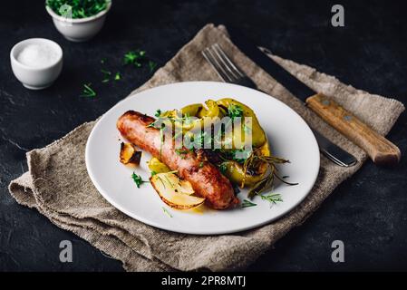 Im Ofen gebackene Schweinewurst mit Paprika, Zwiebeln und verschiedenen Kräutern Stockfoto