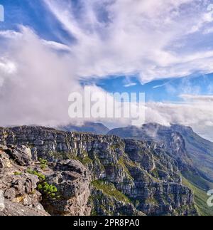 Auf dem Tafelberg in Kapstadt bilden sich dicke Wolken mit viel Platz. Felsiges Gelände an einem sonnigen Tag mit bewölkten Schatten, friedliche Natur in Harmonie mit beruhigendem Blick auf Pflanzen und Landschaft Stockfoto